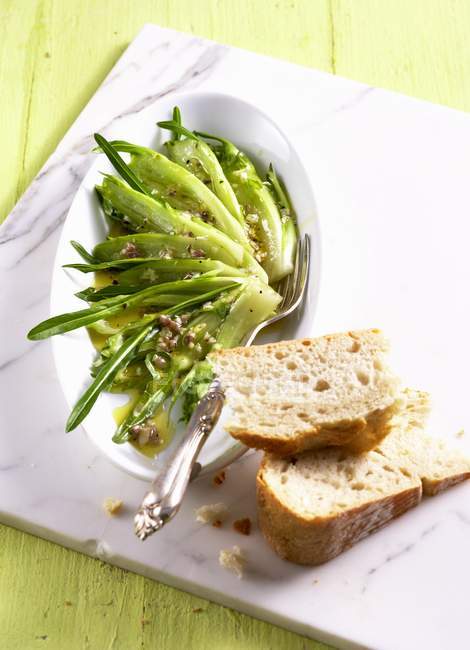 Puntarelle alla Romana with an anchovy dressing on white chopping board — Stock Photo