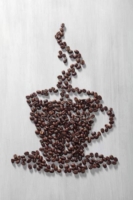 Granos de café dispuestos en forma de taza - foto de stock