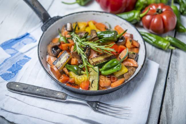 Смажені овочі з грибами та розмарином на сковороді над рушником — стокове фото