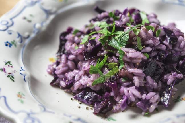 Red cabbage risotto with basil  on white plate over table — Stock Photo