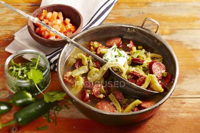 Sopa de chorizo con nopales - soup with sausages and prickly pear greens in plate on wooden surface — Stock Photo