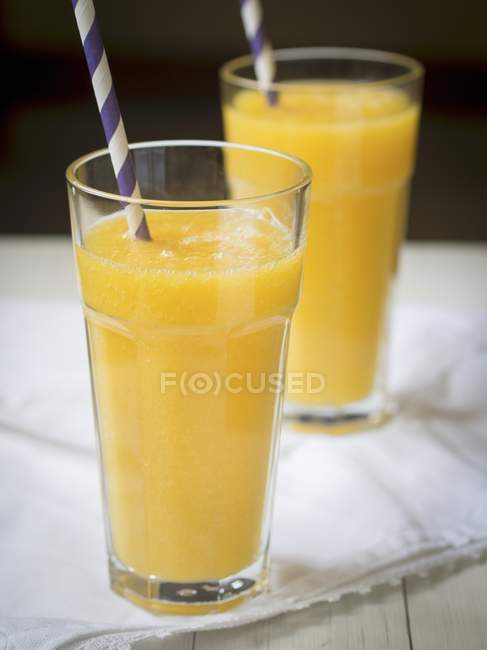 Yellow tropic fruit smothie in two tall glasses. — Stock Photo