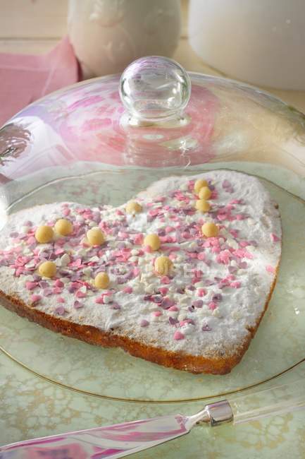 Heart-shaped cake with pink sugar hearts — Stock Photo