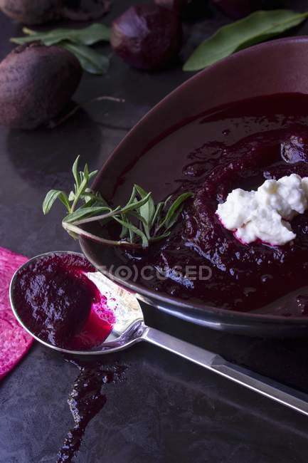 Beetroot soup in a soup bowl with crme frache on black plate — Stock Photo