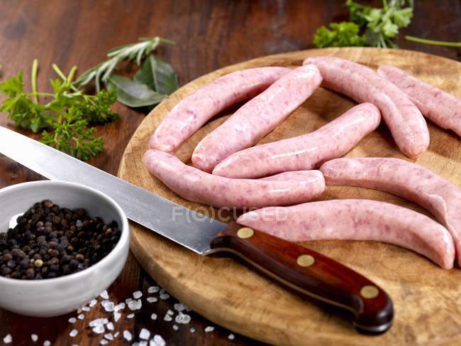 Raw sausages on chopping board — Stock Photo
