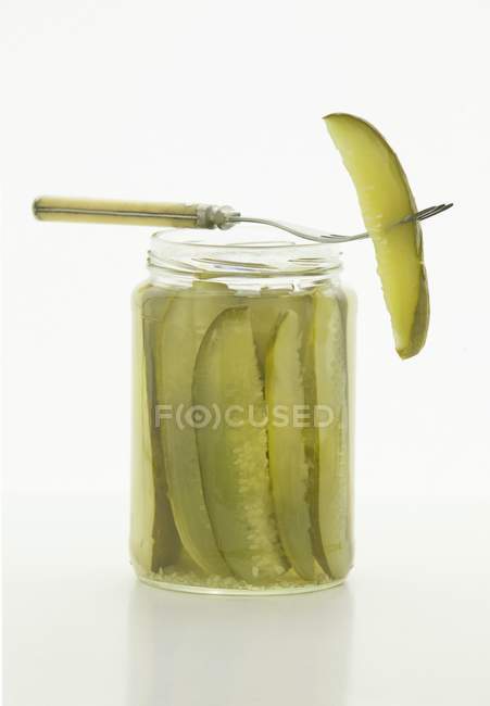 Dill Pickles em frasco com garfo no fundo branco — Fotografia de Stock