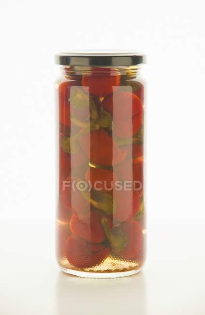 Hot sweet pickled peppers on white surface — Stock Photo
