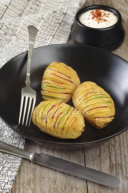 Pommes de terre Hasselback farcies sur plaque noire avec fourchette — Photo de stock