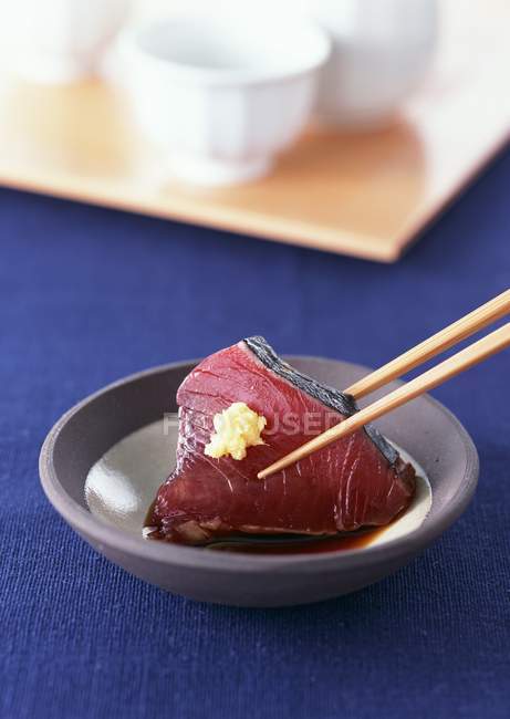 Closeup view of pouring seared Bonito fish slice in sauce with chopsticks — Stock Photo