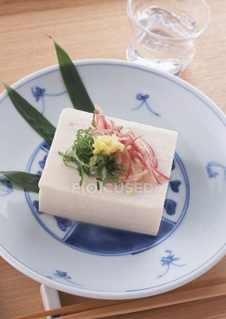 Тофу на біло-синій тарілці над дерев'яним столом — стокове фото