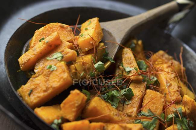 Sweet potato curry with coriander and African wooden bowl with a wooden spoon — Stock Photo
