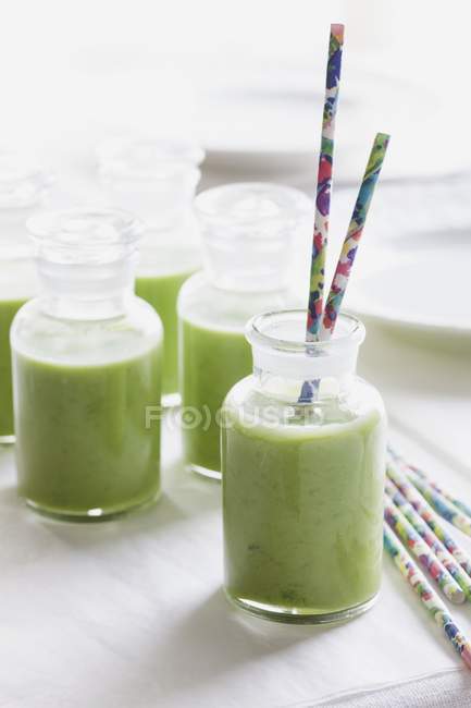 Cold pea soup in bottles with straws — Stock Photo