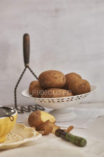 Teilweise geschälte Kartoffeln mit Schäler — Stockfoto
