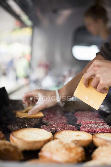 Beefburgers being topped with cheese — Stock Photo