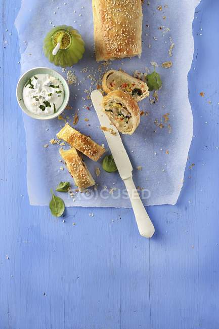 Uno strudel di pasta sfoglia vegetale su carta su superficie blu — Foto stock