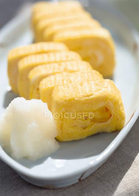 Flavored Rolled Egg on white plate over textile surface — Stock Photo