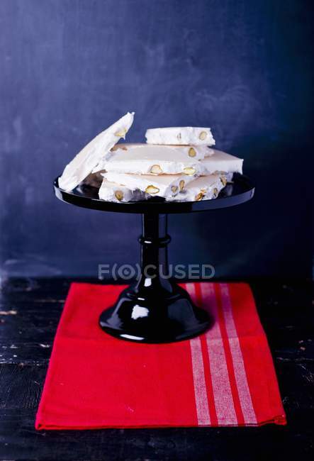 Closeup view of nougat with nuts on cake stand and red towel — Stock Photo