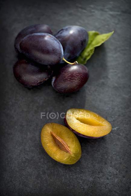 Ameixas maduras frescas com metades — Fotografia de Stock