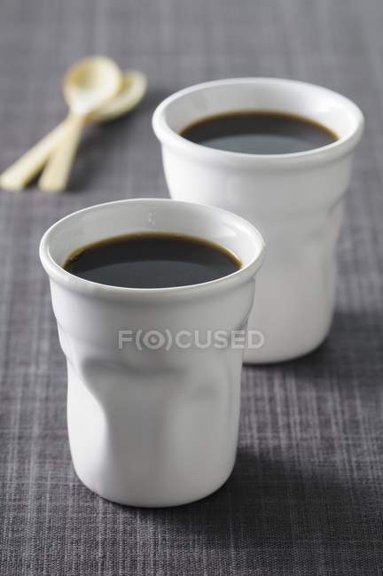 Black coffee into ceramic cups — Stock Photo