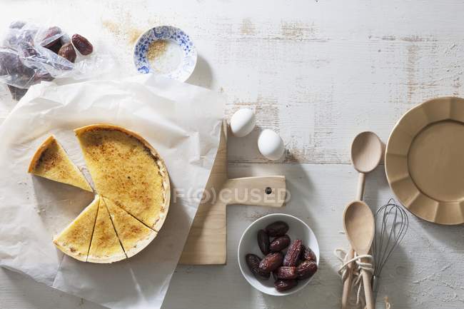 Crme brle tart and dates over wooden surface with wooden desk and paper — Stock Photo