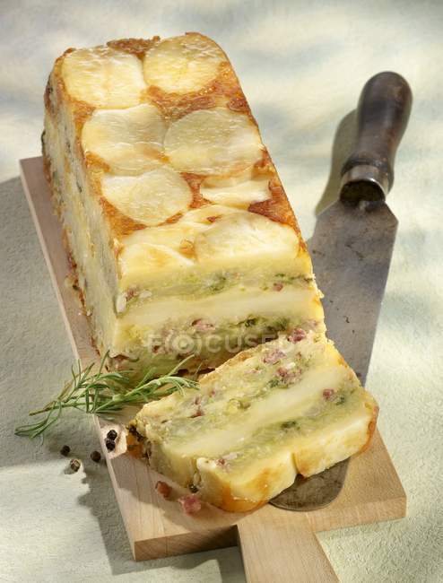 Closeup view of potato cake with bacon and nuts on cutting board — Stock Photo
