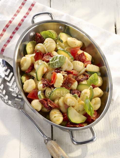 Vegetarian summer gnocchi with courgettes in metal dish over wooden white surface — Stock Photo