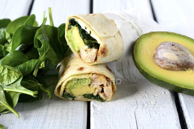 Chicken, spinach and avocado wraps over wooden surface — Stock Photo