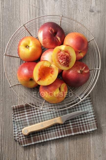 Fresh nectarines in wire basket — Stock Photo