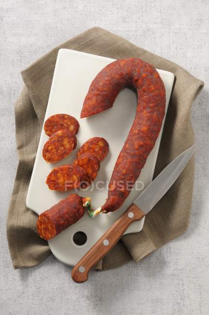 Vue du haut du Chorizo espagnol avec un couteau sur une planche à découper — Photo de stock