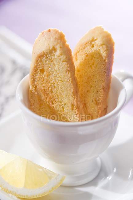 Closeup view of vanilla Biscotti in white cup and lemon wedge — Stock Photo