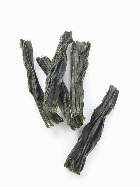 Nahaufnahme von oben von getrockneten Wakame-Algen auf weißer Oberfläche — Stockfoto