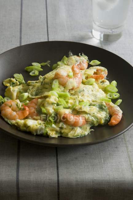 Prawn and spring onion omelette on black plate over towel — Stock Photo