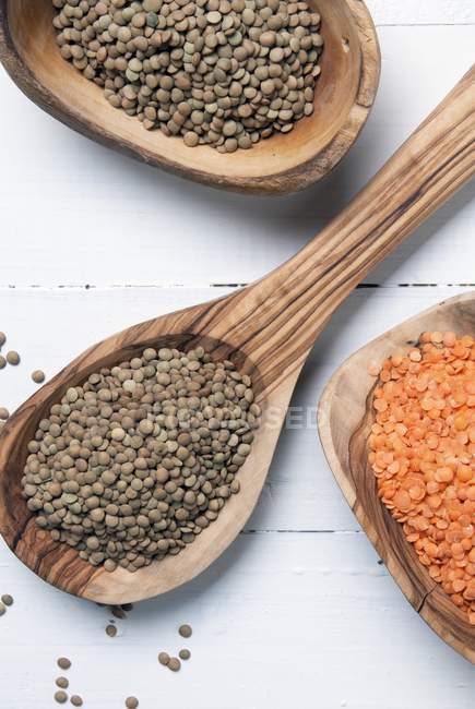 Closeup top view of red and green lentils on wooden spoons — Stock Photo