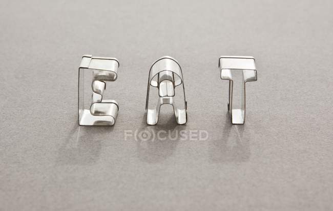 Close up view of the word EAT made with letter shaped cookie cutters — стоковое фото