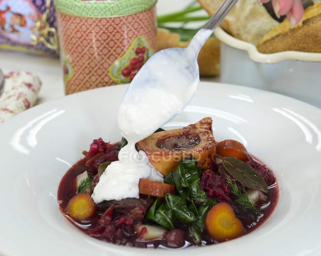Borscht with sour cream for Easter  on white plate with spoon — Stock Photo