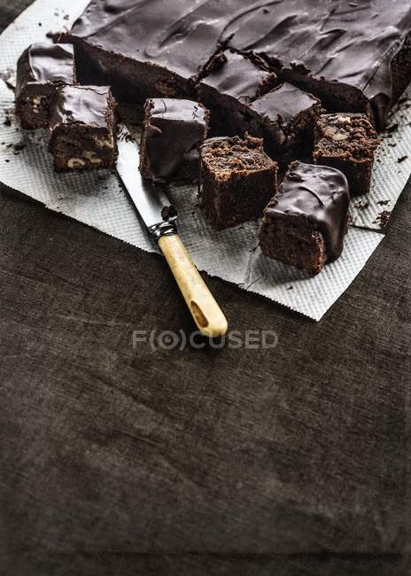 Brownies serving on kitchen paper with a knife — Stock Photo