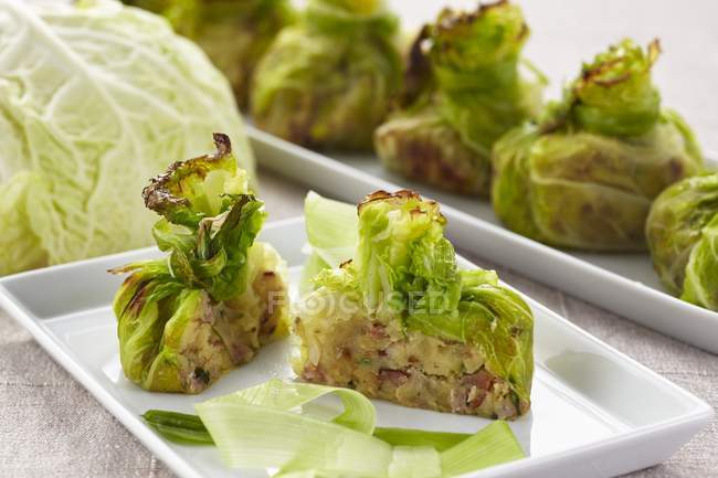 Stuffed, gratinated cabbage parcels on white plates — Stock Photo
