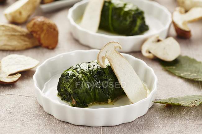 Rollos de espinacas con un relleno de champiñones porcini en platos blancos - foto de stock