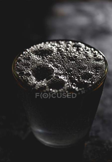 Closeup view of black fizzy water in glass — Stock Photo