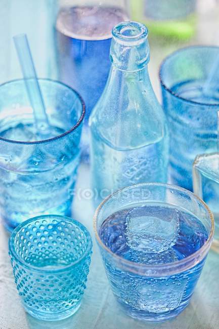 Vista de cerca de las bebidas azules en vasos y botellas - foto de stock