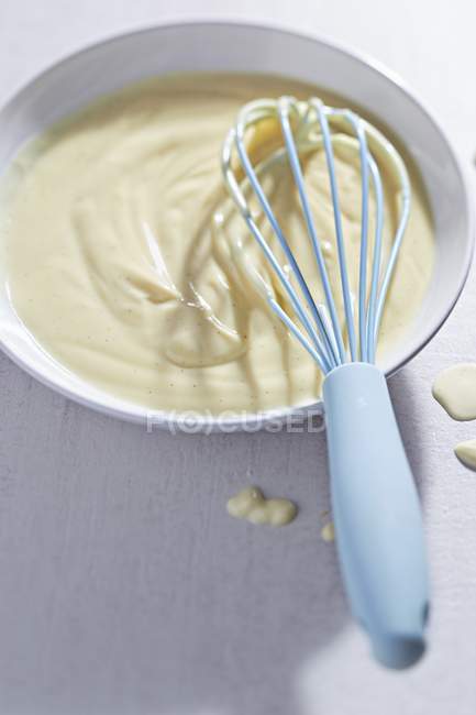 Primo piano vista di salsa alla vaniglia con frusta in ciotola — Foto stock