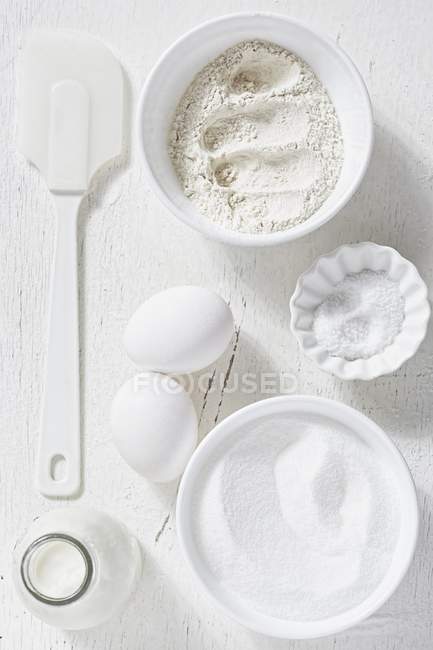 Вид сверху на различные ингредиенты для выпечки с лопаткой на белой поверхности — стоковое фото