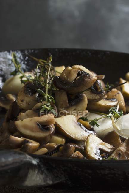 Жареные грибы с тимьяном в чугунной сковороде — стоковое фото