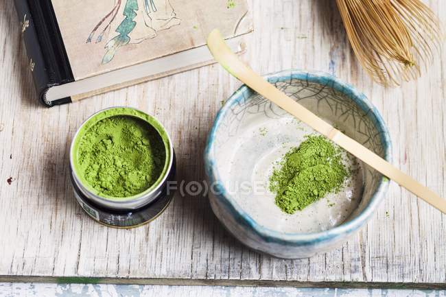 Elevated view of Matcha tea powder in bowl and tin — Stock Photo