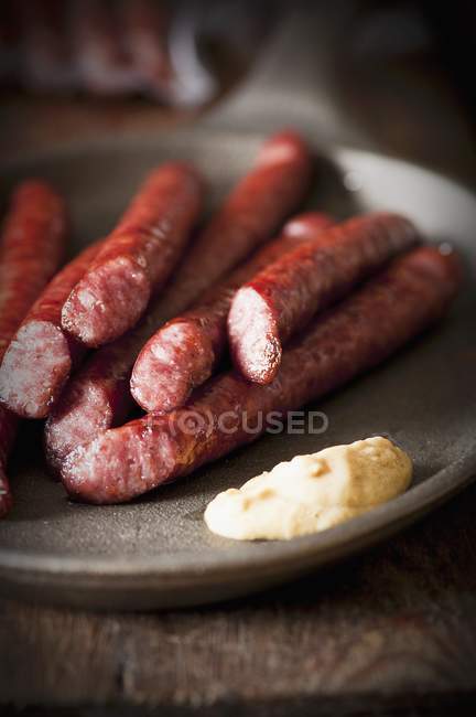 Thin grilled sausages with mustard — Stock Photo