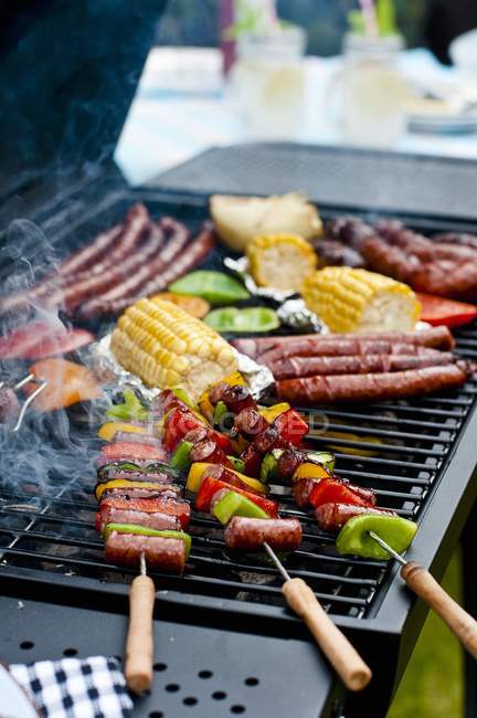Kebabs de salsicha, salsichas e legumes em um churrasco ao ar livre — Fotografia de Stock