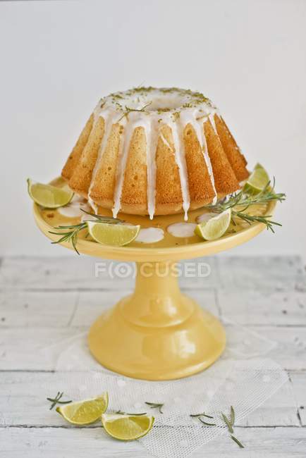 Vue rapprochée de baba avec des limes et du romarin sur le stand de gâteau — Photo de stock