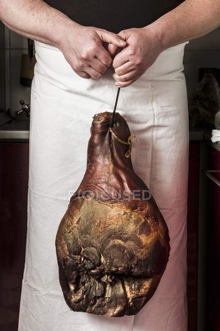 Man in apron holding leg — Stock Photo
