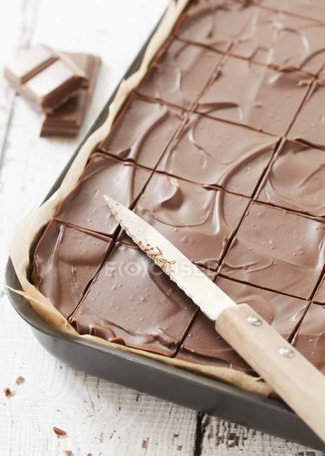 Vista close-up de corte de torta de chocolate e faca na assadeira — Fotografia de Stock