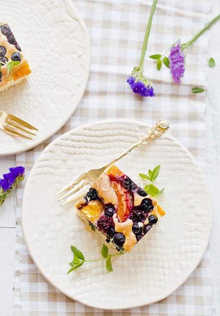 Fruit cake on plate with silver fork — Stock Photo